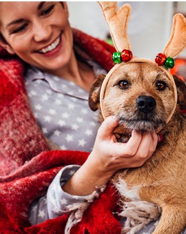 Woman with dog in wearing felt antlers.